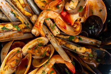 Sauteed shellfish and seafood in a black pan on a white background 