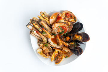 Sauteed shellfish and seafood in a white plate on a white background