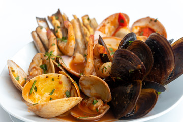Sauteed shellfish and seafood in a white plate on a white background