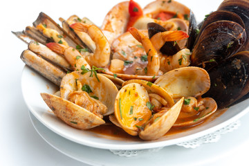 Sauteed shellfish and seafood in a white plate on a white background