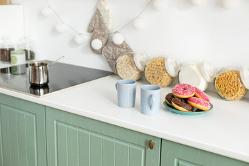 Two coffee cups and donuts in the kitchen