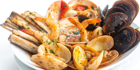 Sauteed shellfish and seafood in a white plate on a white background