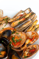 Sauteed shellfish and seafood in a white plate on a white background