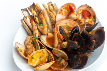 Sauteed shellfish and seafood in a white plate on a white background
