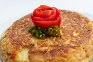 Tortilla espanola, spanish omelette with potatoes with a tomato flower on top
