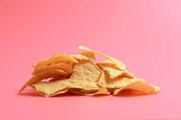 A heap of nachos chips on pink background