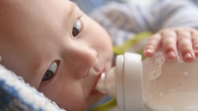A mother feeds her baby milk from a bottle. Close-up