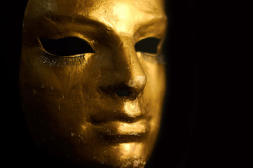 Golden mask close-up on a black background.
