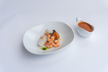 Fancy FISH AND SEAFOOD with soup on a white plate with a white background