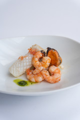 Fancy FISH AND SEAFOOD with soup on a white plate with a white background