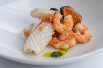 Fancy FISH AND SEAFOOD with soup on a white plate with a white background