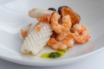 Fancy FISH AND SEAFOOD with soup on a white plate with a white background
