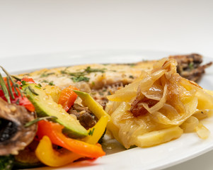 Sole meunière fish with grilled vegetables and caramelized onions on a white plate with white background