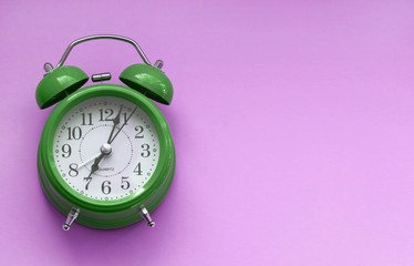Green alarm clock on pink background.