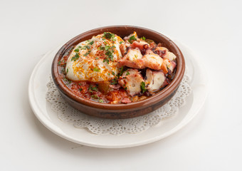 Octopus ratatouille with an egg in a clay pot dish with a white background