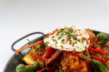 lobster cassolette, potatoes and fried eggs on a pan with white background. Caldereta de bogavante de formentera.