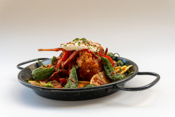 lobster cassolette, potatoes and fried eggs on a pan with white background. Caldereta de bogavante de formentera.