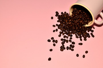 Shot of a pink cup with coffee beans on pink background