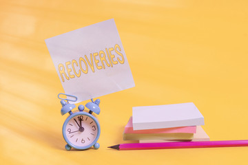 Text sign showing Recoveries. Business photo text process of regaining possession or control of something lost Alarm clock blank pencil sticky note stacked notepads colored background
