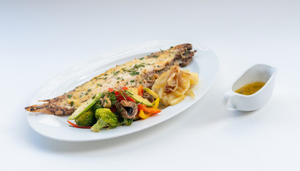 Sole meunière fish with grilled vegetables and caramelized onions on a white plate with white background. LENGUADO MENIER