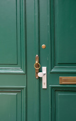 Old metal door handle lock on green wooden door. Door knob