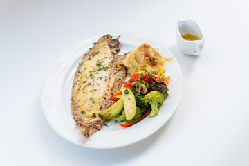 Sole meunière fish with grilled vegetables and caramelized onions on a white plate with white background. LENGUADO MENIER