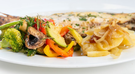Sole meunière fish with grilled vegetables and caramelized onions on a white plate with white background. LENGUADO MENIER