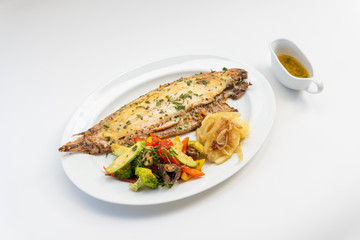 Sole meunière fish with grilled vegetables and caramelized onions on a white plate with white background. LENGUADO MENIER