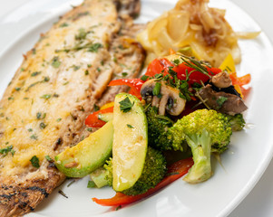 Sole meunière fish with grilled vegetables and caramelized onions on a white plate with white background. LENGUADO MENIER