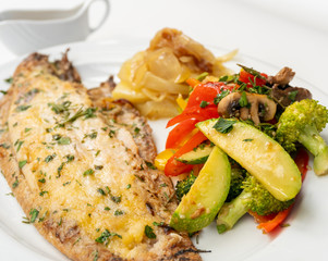 Sole meunière fish with grilled vegetables and caramelized onions on a white plate with white background. LENGUADO MENIER