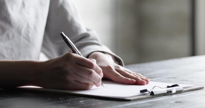 部屋で契約書にサインをする若い女性の手元