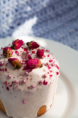 Cake with flowers, beads and nuts. Blue knitted plaid. Cozy Easter, spring still life scene. The concept of the Easter holidays and decor. 