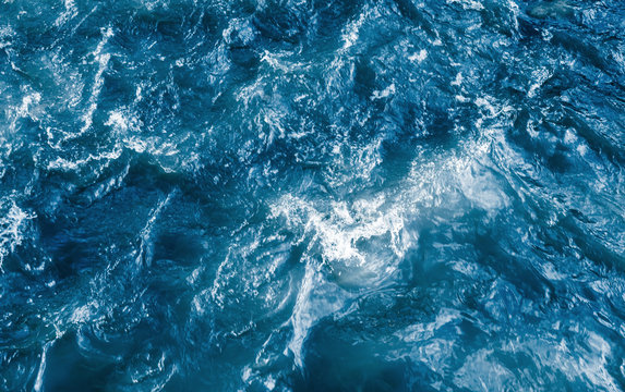 Deep blue stormy ocean water with splashes and foam © evannovostro