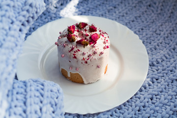 Cake with flowers, beads and nuts. Blue knitted plaid. Cozy Easter, spring still life scene. The concept of the Easter holidays and decor. 