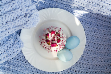 Easter bread, cake and eggs with decor of flowers, beads and nuts. Blue knitted plaid. The concept of the Easter holidays and decor.