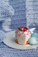 Easter bread, cake and eggs with decor of flowers, beads and nuts. Blue knitted plaid. The concept of the Easter holidays and decor.