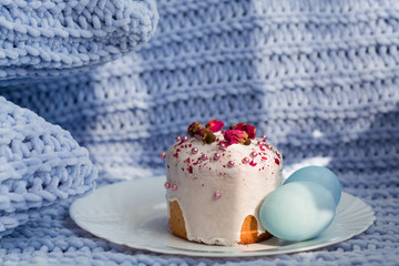 Easter bread, cake and eggs with decor of flowers, beads and nuts. Blue knitted plaid. The concept of the Easter holidays and decor.