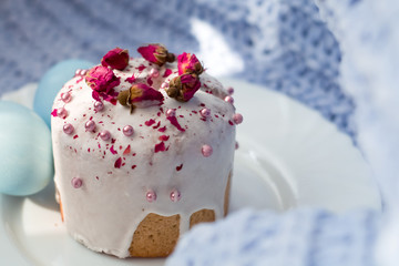 Easter bread, cake and eggs with decor of flowers, beads and nuts. Blue knitted plaid. The concept of the Easter holidays and decor.