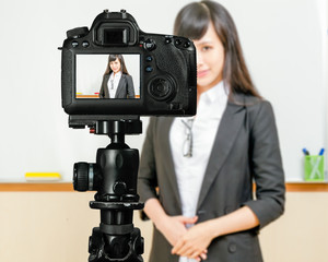 Naklejka premium Asian American teacher streaming class with camera
