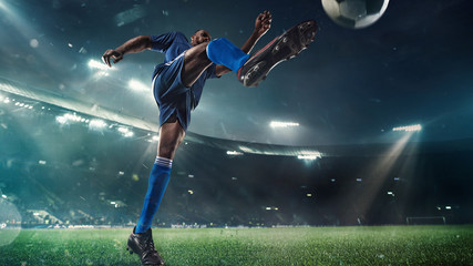 Professional football or soccer player in action on stadium with flashlights, kicking ball for winning goal, wide angle. Concept of sport, competition, motion, overcoming. Field presence effect. © master1305