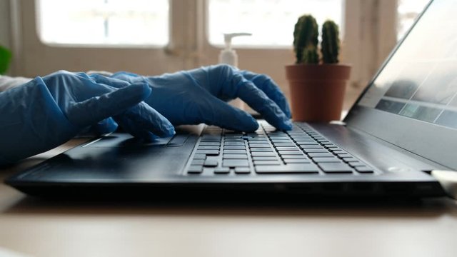 coronavirus smart working, close up of hands typing computer keyboard with hand sanitizer working from home