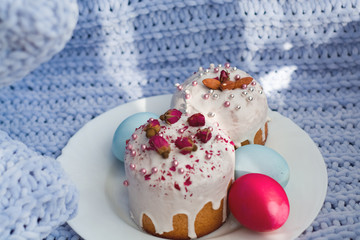 Easter bread, cake and eggs with decor of flowers, beads and nuts. Blue knitted plaid. The concept of the Easter holidays and decor.