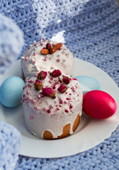Easter bread, cake and eggs with decor of flowers, beads and nuts. Blue knitted plaid. The concept of the Easter holidays and decor.