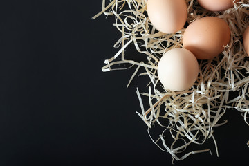 Raw chicken eggs on a black background, top view with place for text.