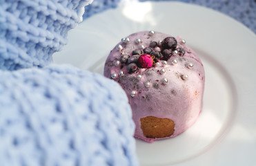 Cake with flowers, beads and nuts. Blue knitted plaid. Cozy Easter, spring still life scene. The concept of the Easter holidays and decor. 