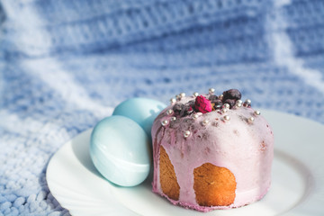 Easter bread, cake and eggs with decor of flowers, beads and nuts. Blue knitted plaid. The concept of the Easter holidays and decor.