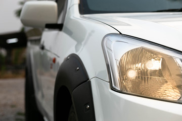 Rear view of a white car, headlights turn on.