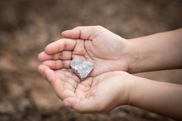 Heart shaped stone held in hands.