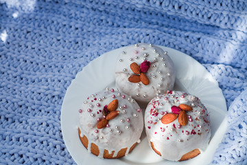 Cake with flowers, beads and nuts. Blue knitted plaid. Cozy Easter, spring still life scene. The concept of the Easter holidays and decor. 