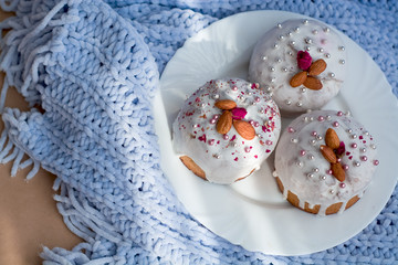 Cake with flowers, beads and nuts. Blue knitted plaid. Cozy Easter, spring still life scene. The concept of the Easter holidays and decor. 